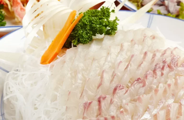 Irisan tipis sashimi Dageumbari (ikan kakap kuning) dihiasi dengan daun parsley, wortel, dan bawang bombay.